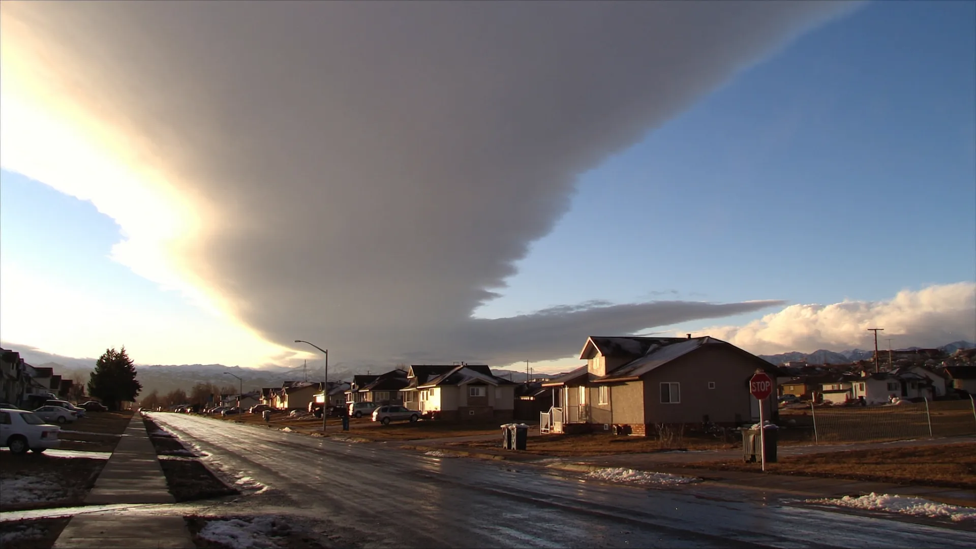A chinook arch over a Calgary street with snow melting on the road