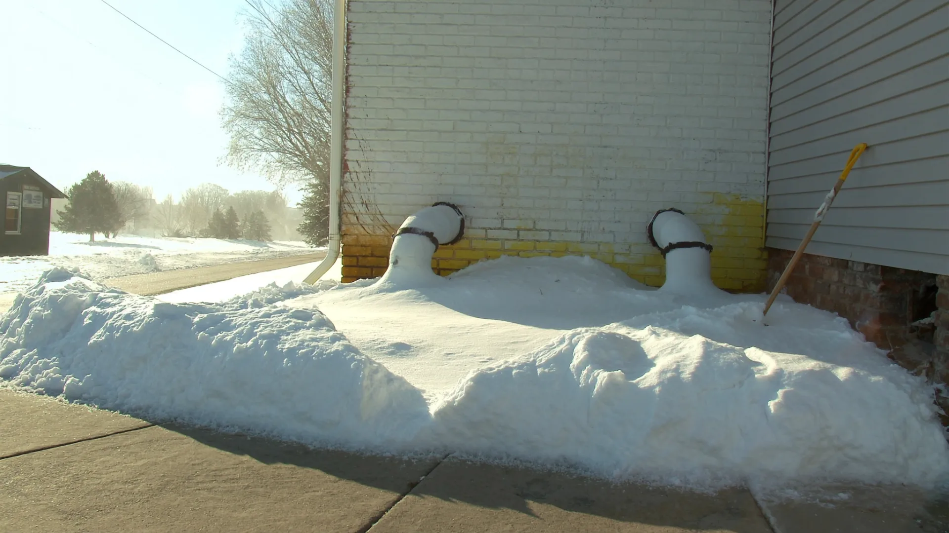 The same vent pipes cleared, with a shovel leaning against the wall