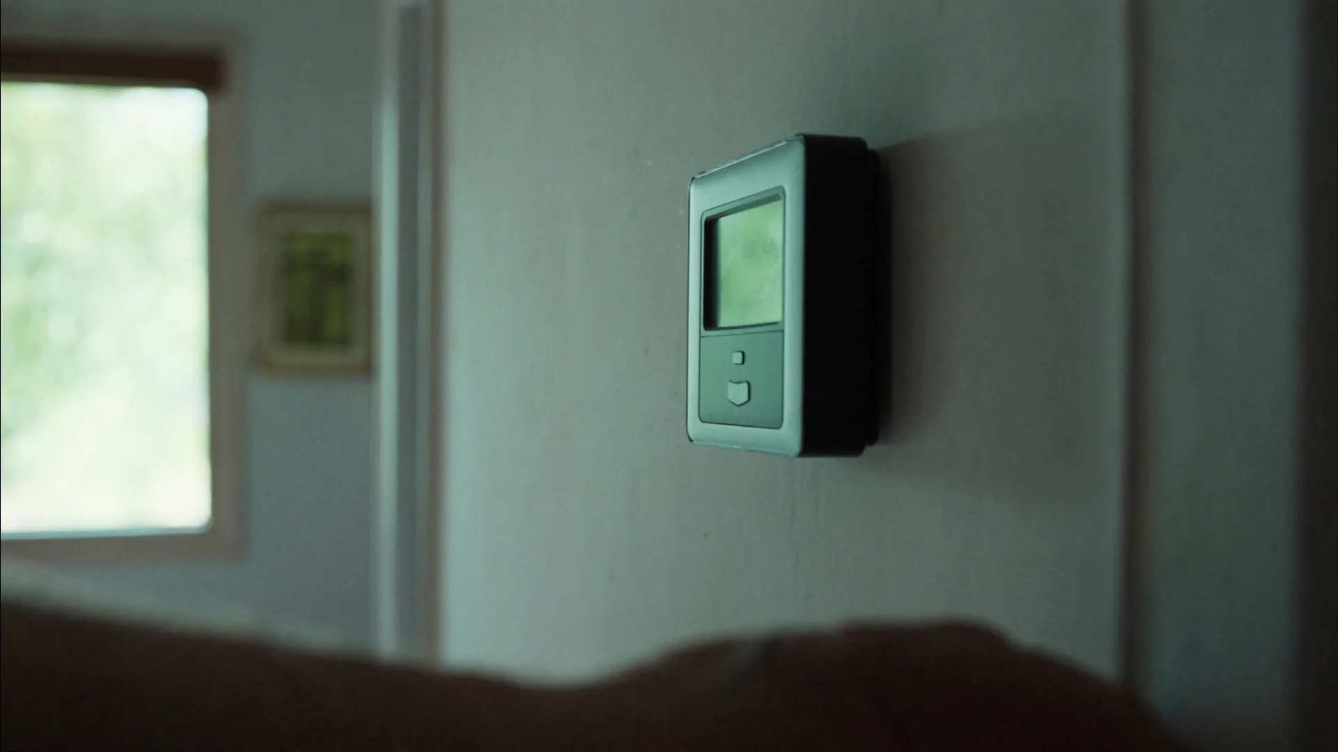 A wall thermostat with a lit display in a home hallway