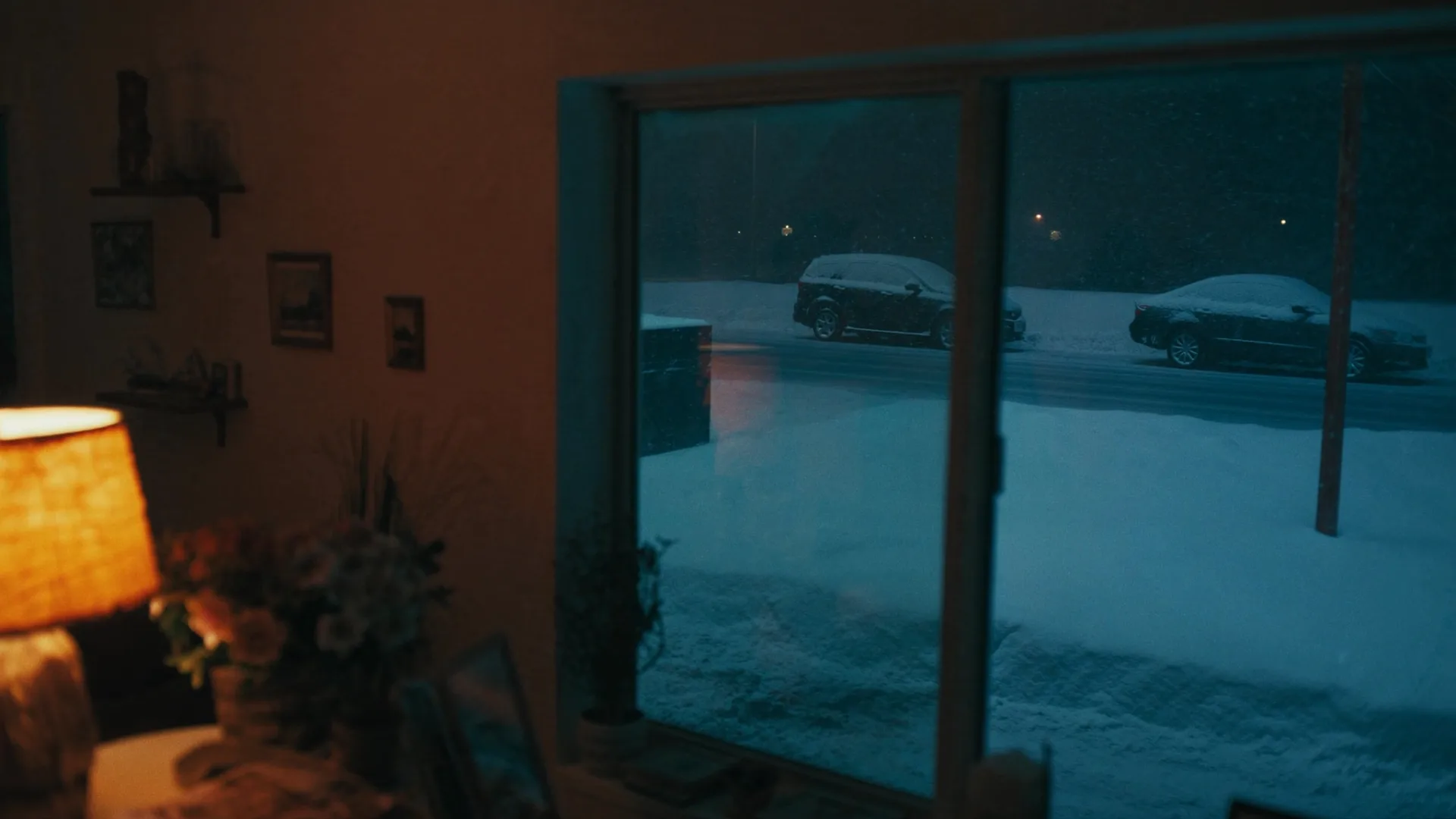A warm lit living room seen against heavy snow falling outside the window
